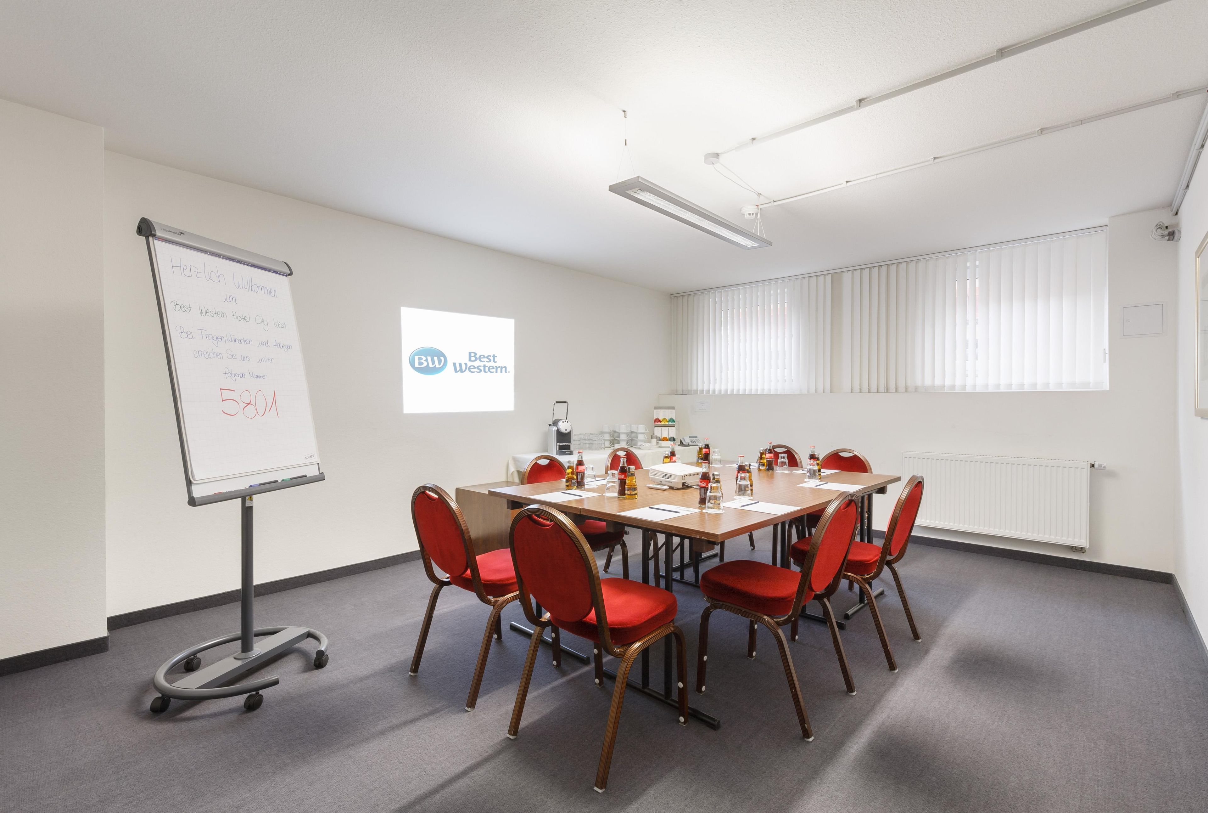 A conference room with a whiteboard, a projector screen, and a table with chairs.
