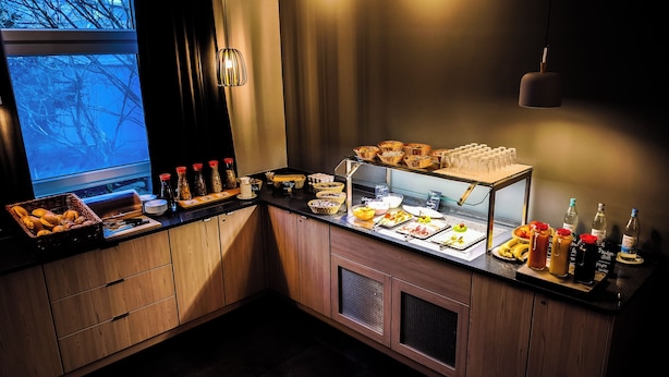 A buffet setup with various food items and beverages, including bread, pastries, and a selection of drinks. - CVJM Düsseldorf Hotel & Tagung (Düsseldorf)