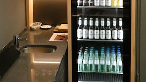 A minibar with a variety of bottled beverages and glasses. - CVJM Düsseldorf Hotel & Tagung (Düsseldorf)