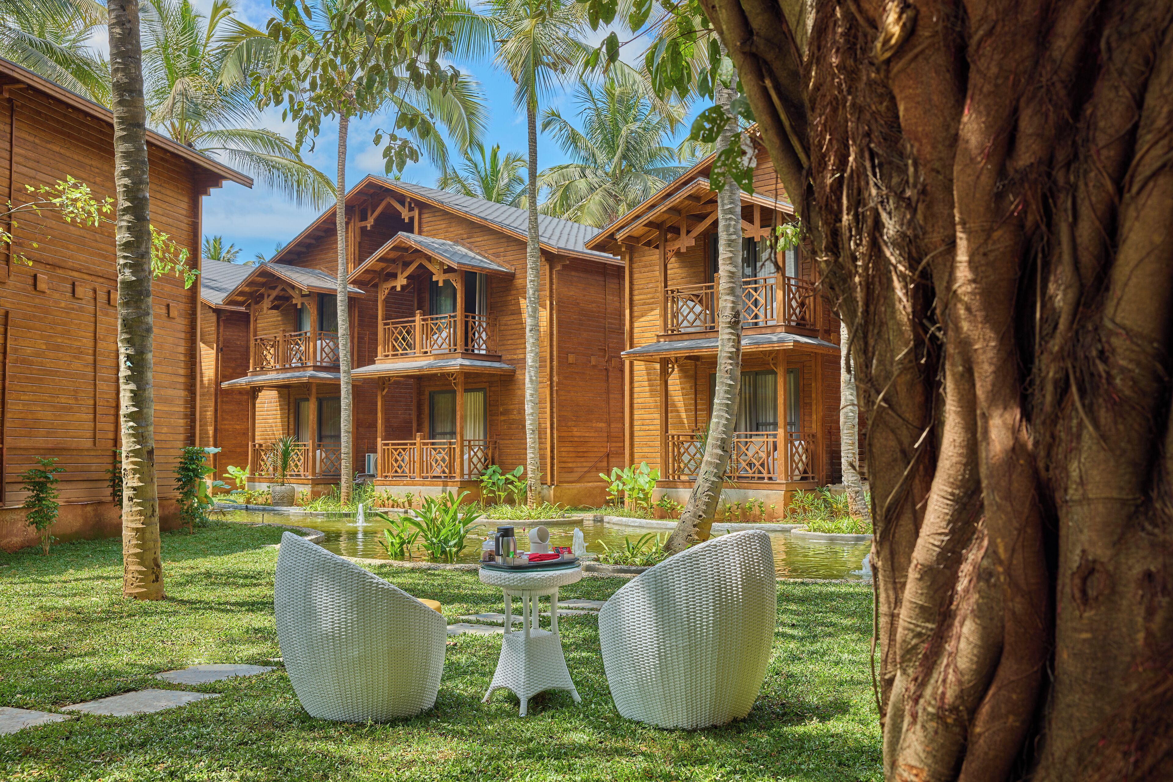 A wooden bungalow with balconies, a small garden, and a pond.