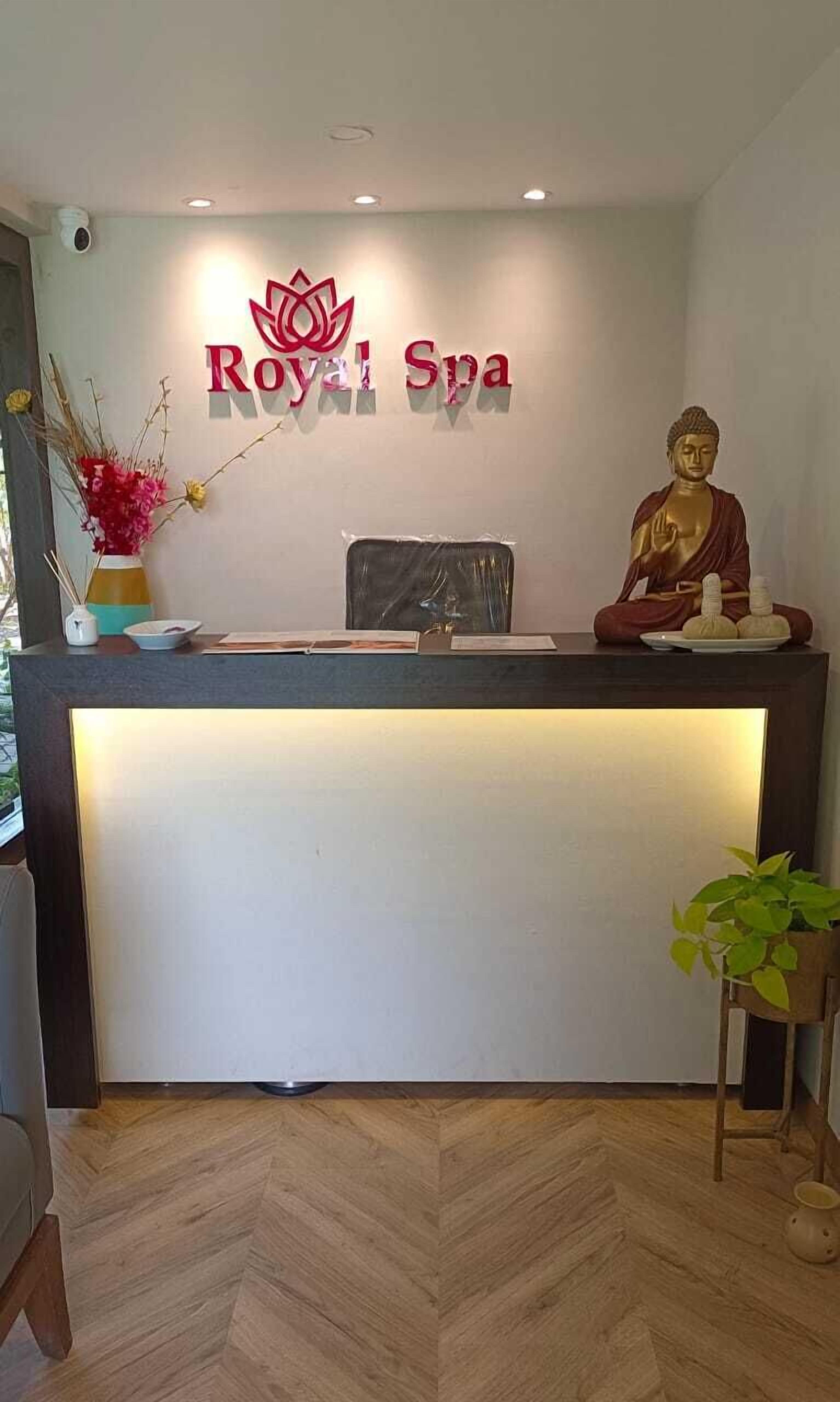 A reception desk with a logo for 'Royal Spa' and a Buddha statue.