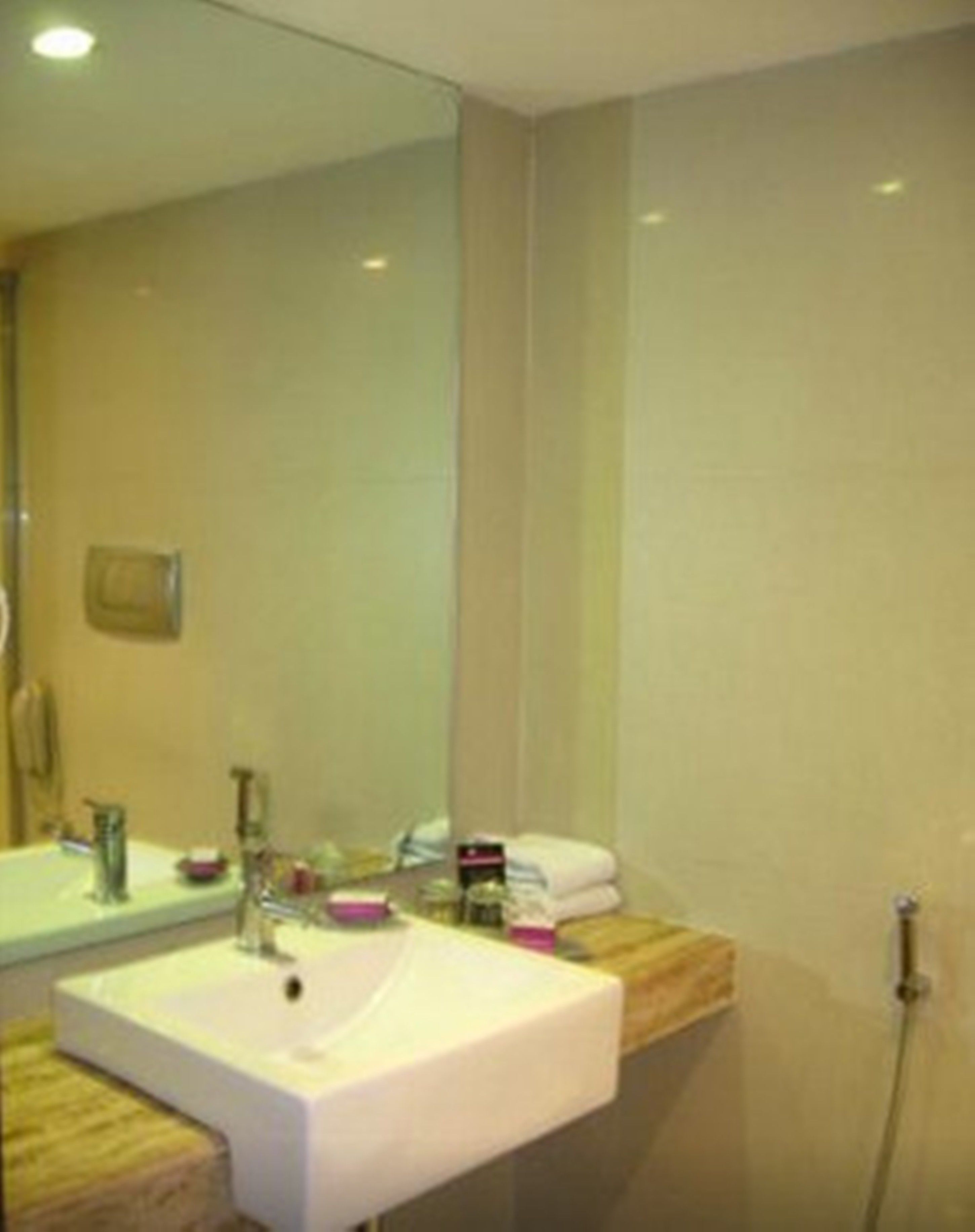 A bathroom with a white sink, a mirror, and a wooden countertop.