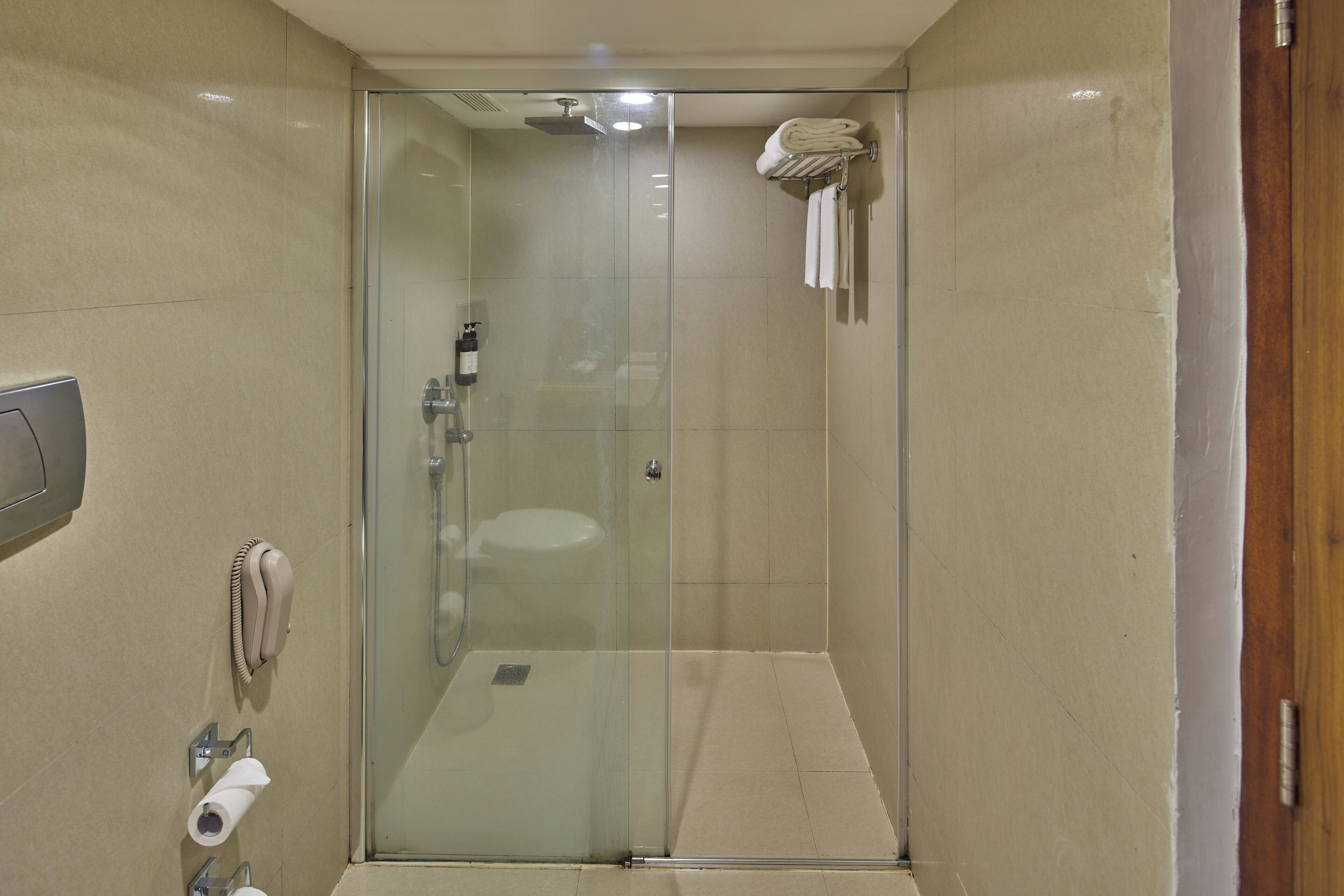 A modern bathroom with a glass-enclosed shower, a toilet, and a towel rack with folded towels.