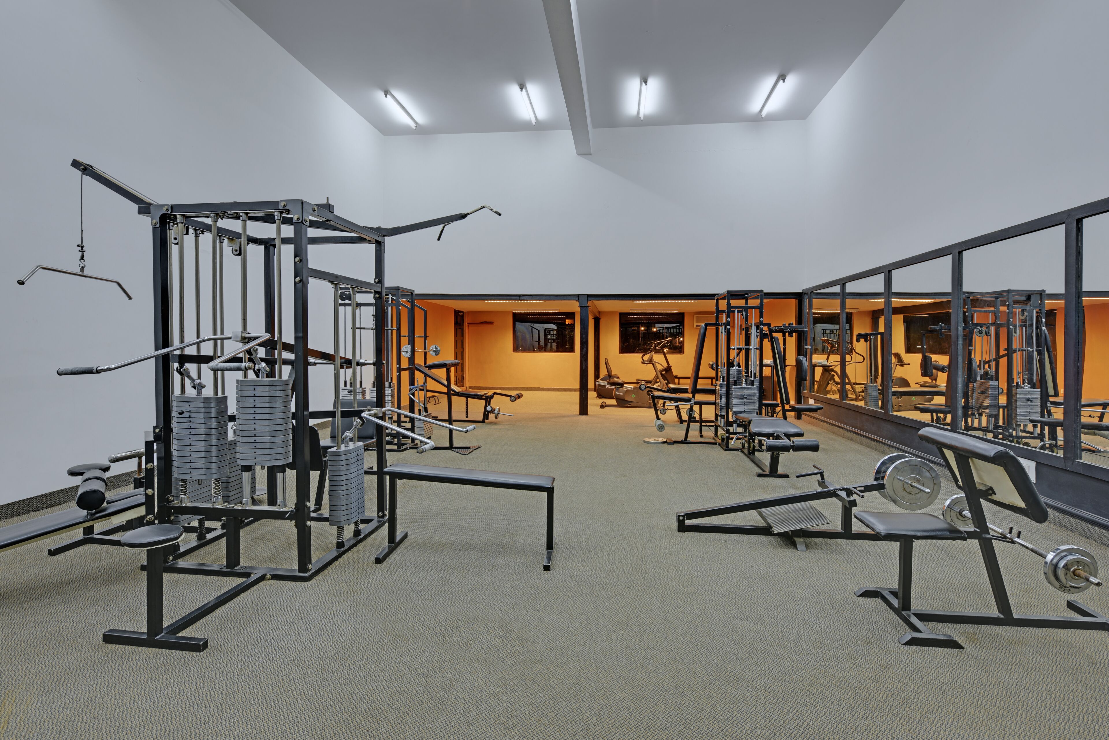 Une salle de sport équipée de divers appareils d’exercice, notamment des machines de musculation et des bancs.
