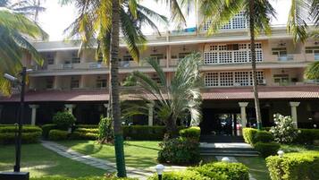 A multi-story hotel with a central courtyard, palm trees, and well-maintained gardens.