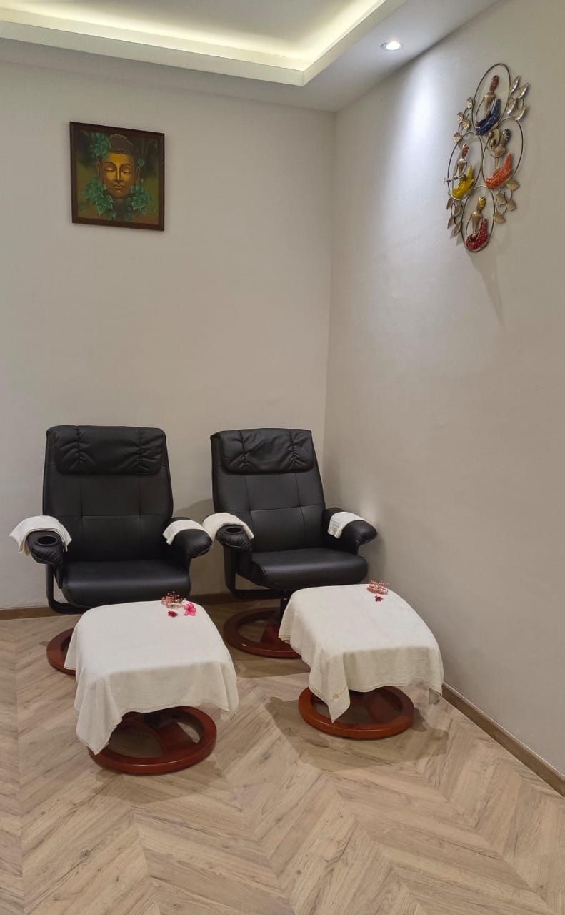 A room with two black leather chairs and two small tables with white tablecloths.