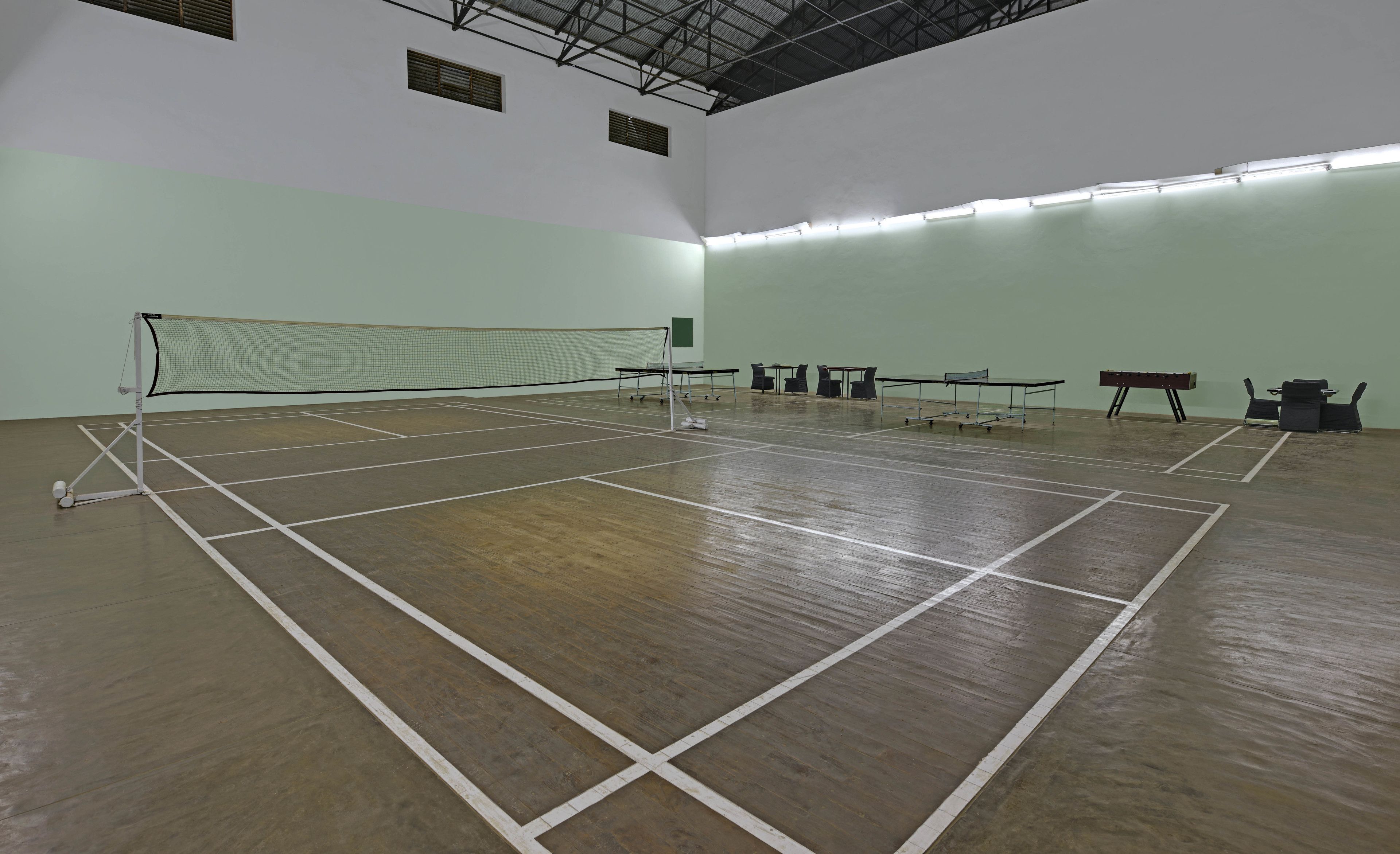 Ein Hallen-Tennisplatz mit Netz, mehreren Tischen und Stühlen.