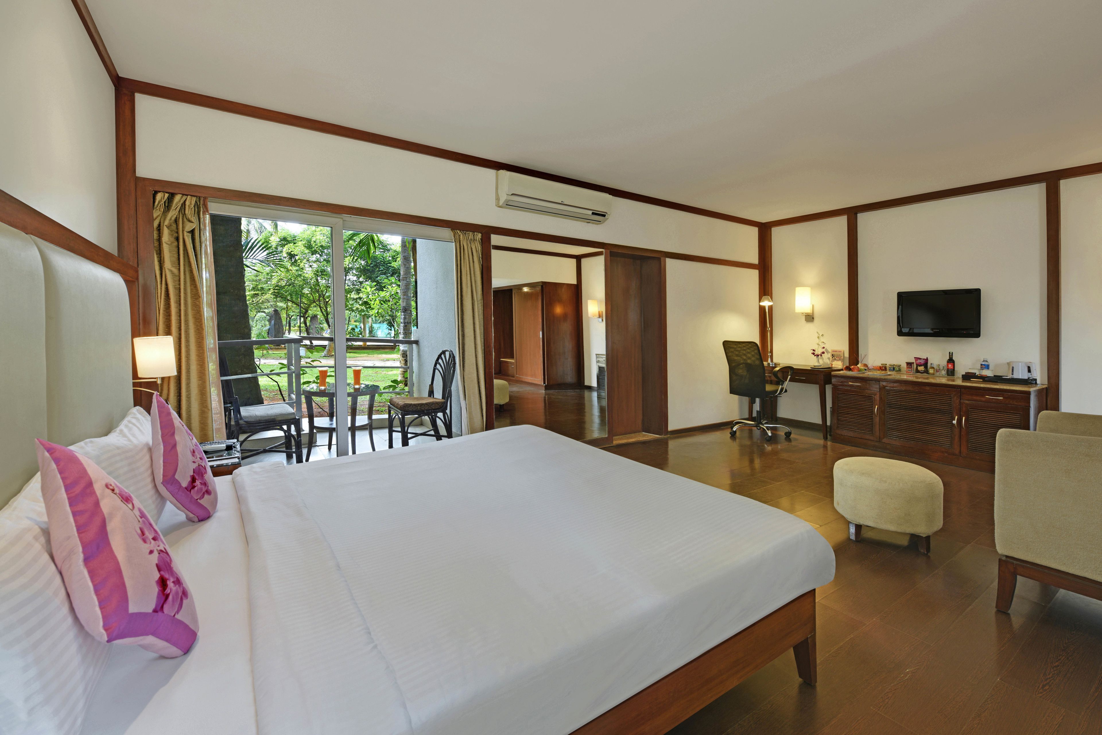 A hotel room with a large bed, a desk, a chair, and a TV.