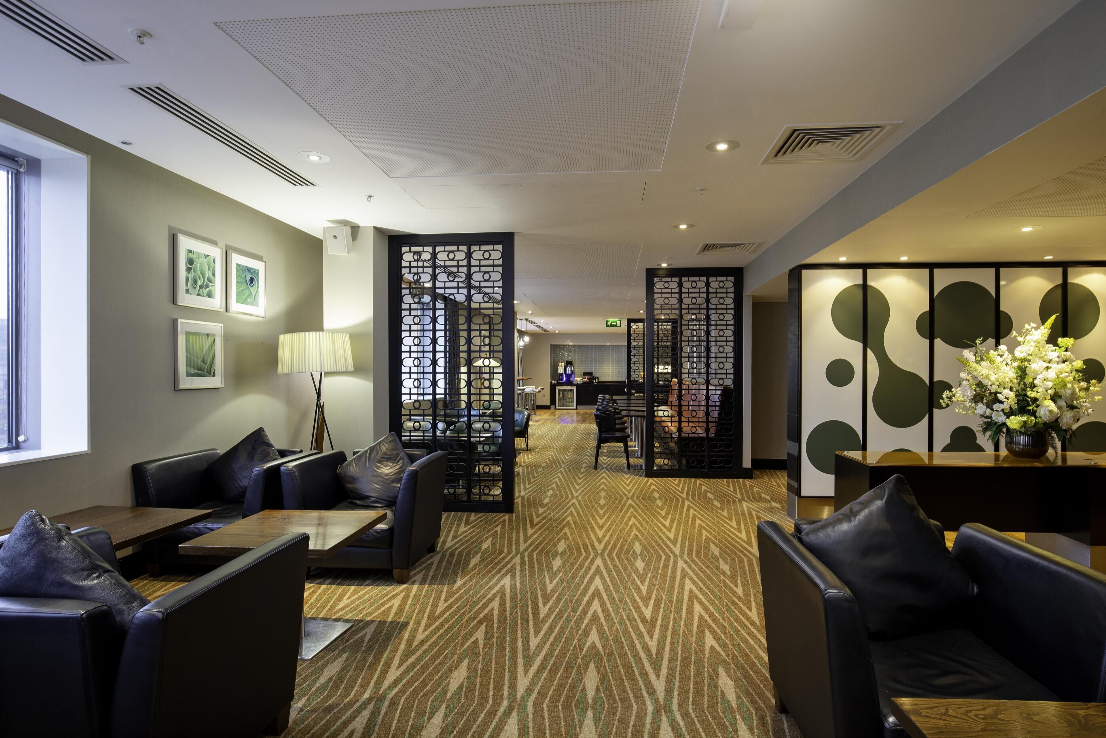 A hotel lobby with seating areas, a reception desk, and a decorative partition.