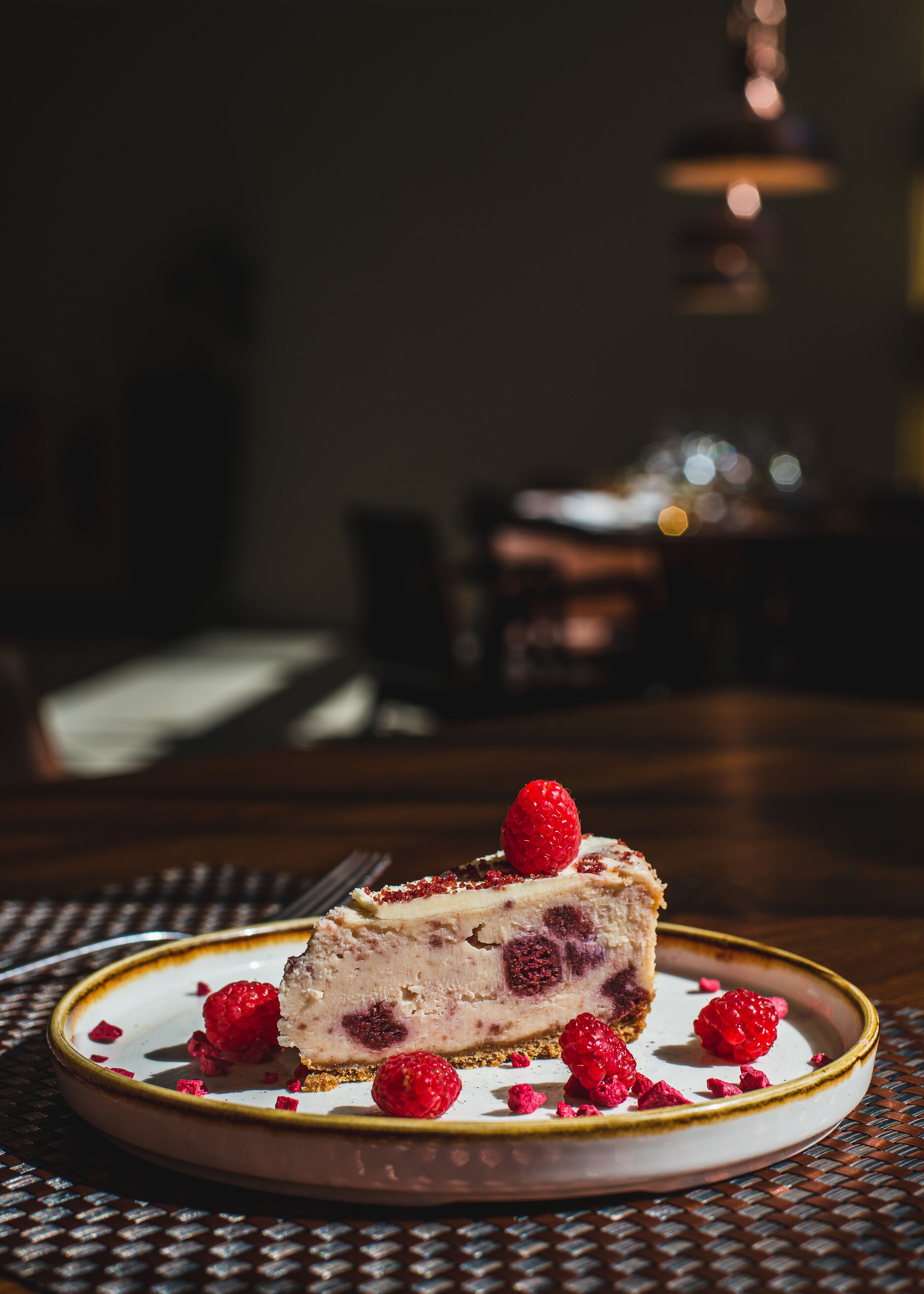 A slice of cheesecake with raspberries on a plate.