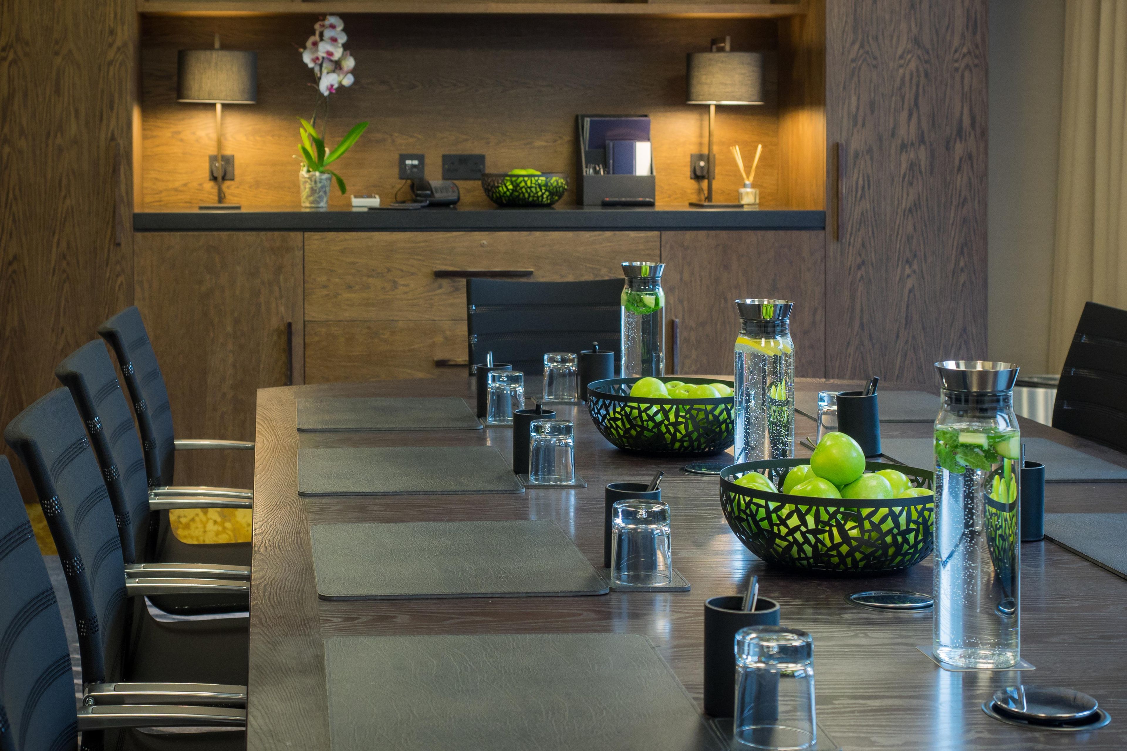 Un espace repas moderne avec une longue table, des chaises, ainsi que divers verres et bols.