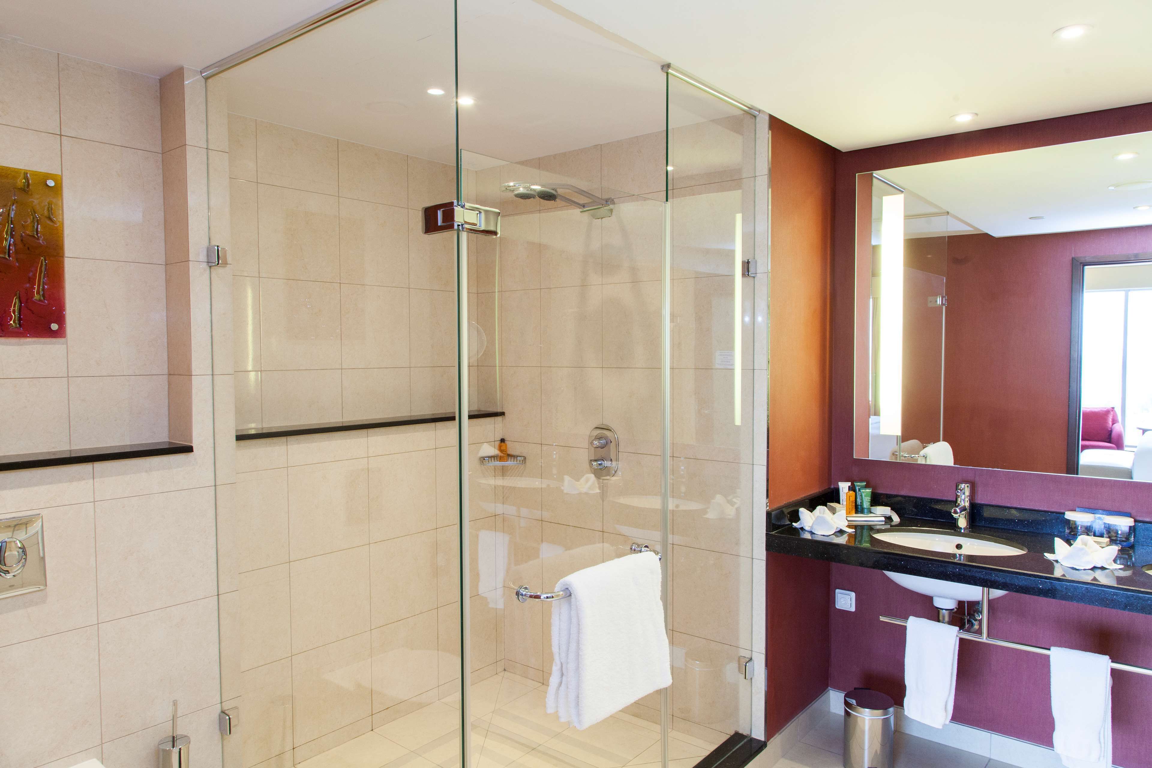 A modern bathroom with a glass-enclosed shower, a vanity with a sink, and a mirror above the sink.