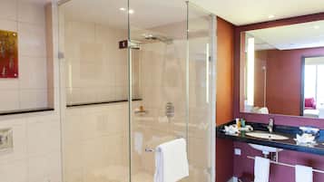 A modern bathroom with a glass-enclosed shower, a vanity with a sink, and a mirror above the sink.