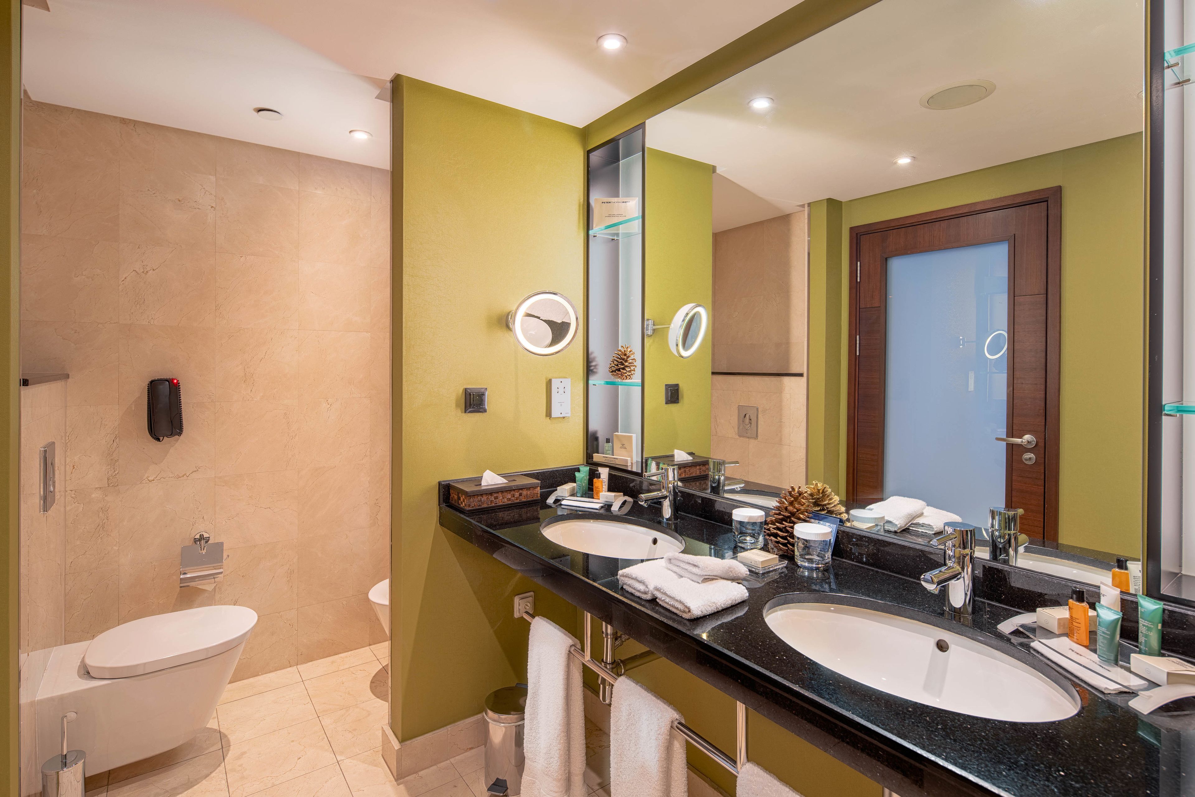 Un baño moderno con dos lavamanos, un inodoro y un espejo grande.