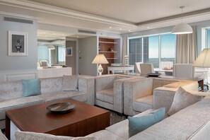 A modern living room with a sectional sofa, a wooden coffee table, and a view of the city through large windows. - Hilton Warsaw City (Warsaw)