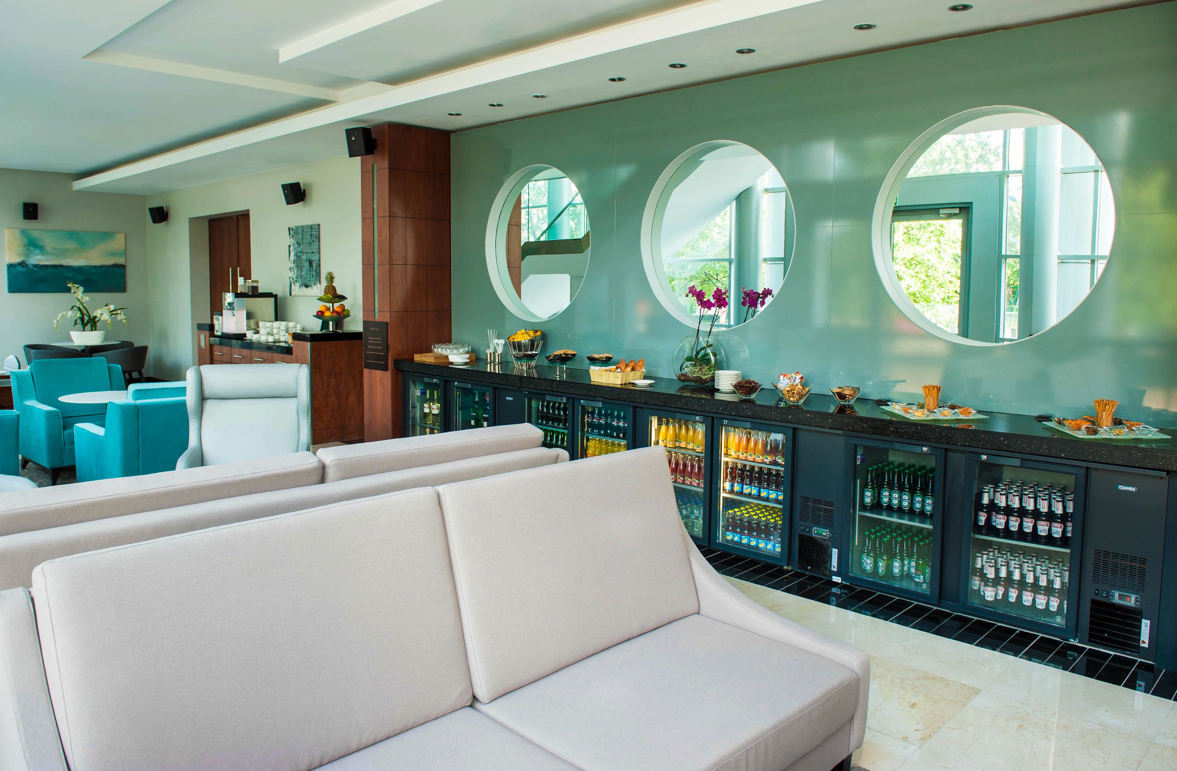 A modern bar area with a sofa, seating, and a bar counter with various items.