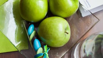 A glass plate with three green apples and a blue and green ribbon, a clear glass, and a laptop on a wooden table.