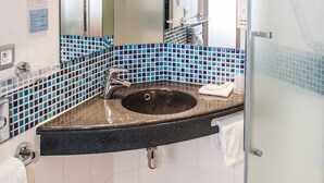 Une salle de bain moderne avec une douche à l’italienne en verre, un lavabo sur plan de toilette noir et des murs recouverts de carreaux bleus.