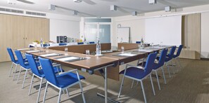 A conference room with a long table, blue chairs, and a whiteboard.