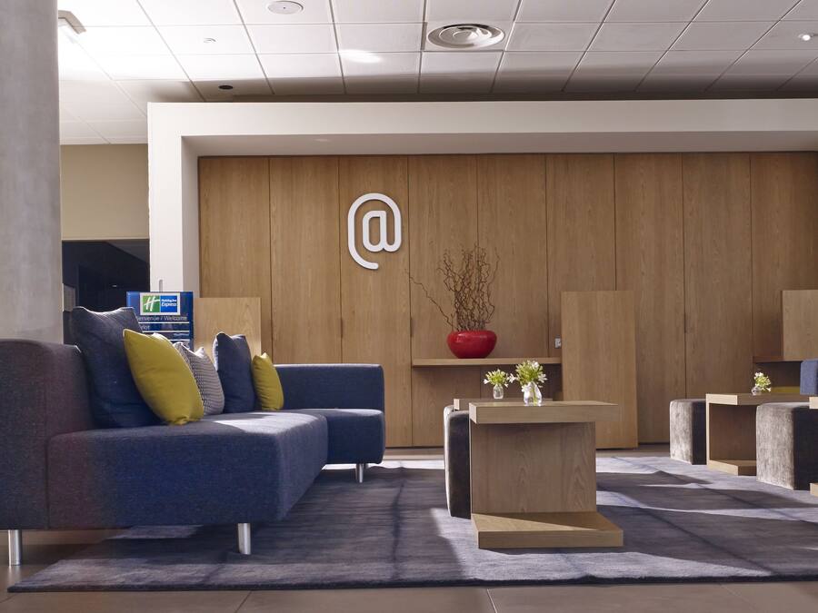 A modern lobby with a reception desk, sofas, and potted plants.