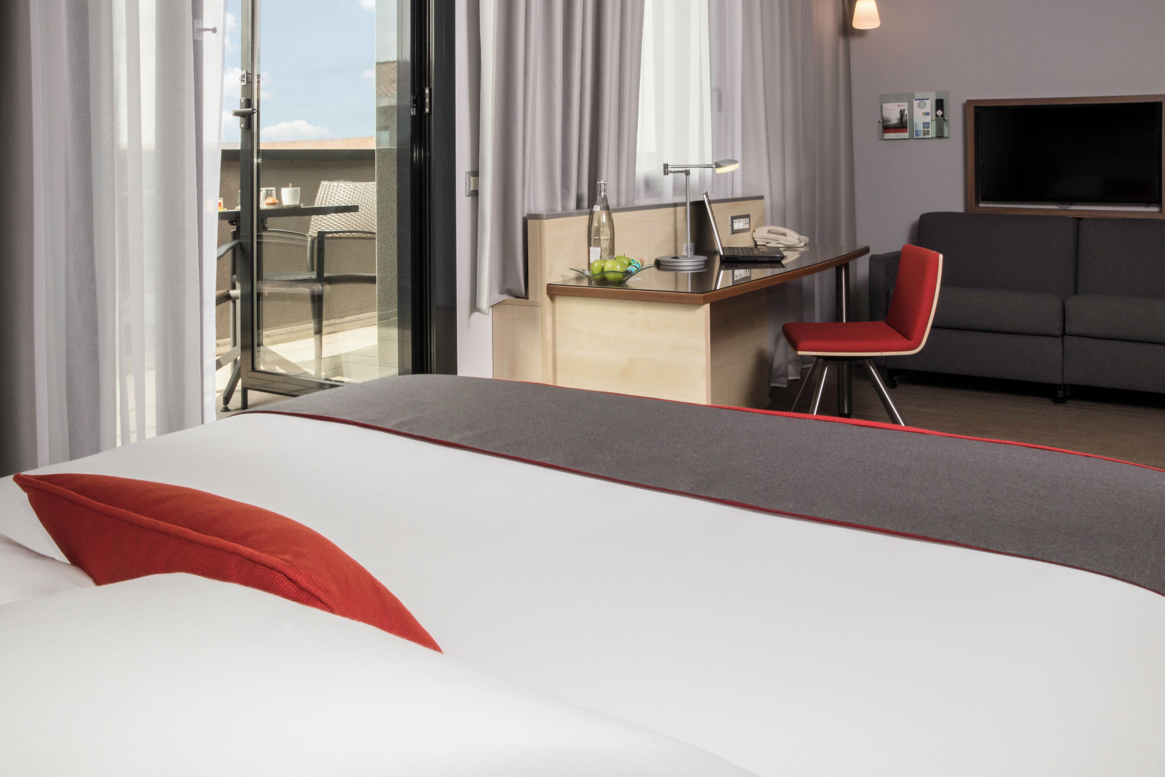 Una habitación de hotel con una cama, un escritorio, una silla y un sofá.