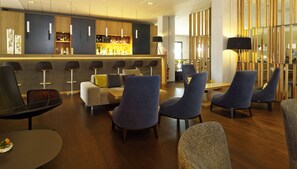 Un espace lounge moderne comprenant des sièges, un bar et une cloison en bois.