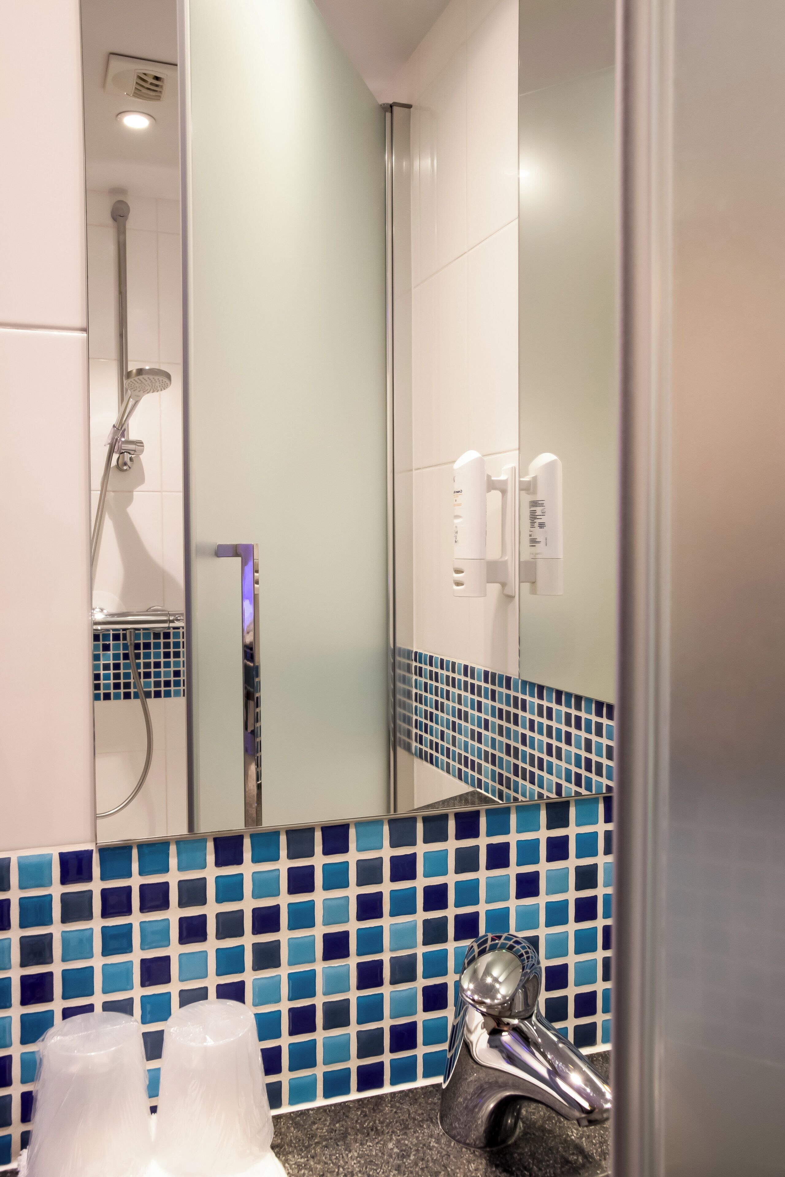 Un baño con ducha, espejo y lavamanos.
