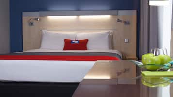 Una habitación de hotel con una cama, una mesita de noche, una lámpara y un frutero.
