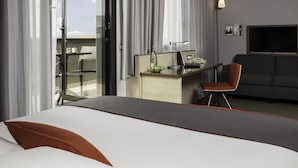 A hotel room with a bed, a desk with a laptop, a chair, and a TV. - Holiday Inn Express Toulouse Airport by IHG (Blagnac)