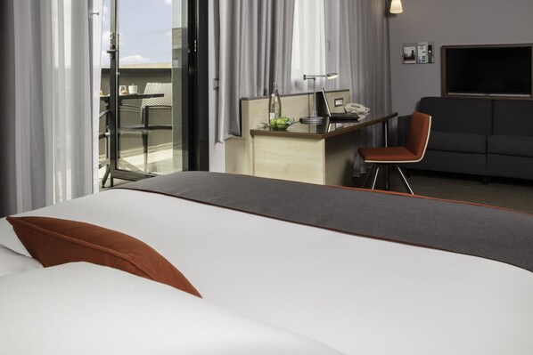 Une chambre d’hôtel avec un lit, un bureau avec un ordinateur portable, une chaise et un téléviseur.