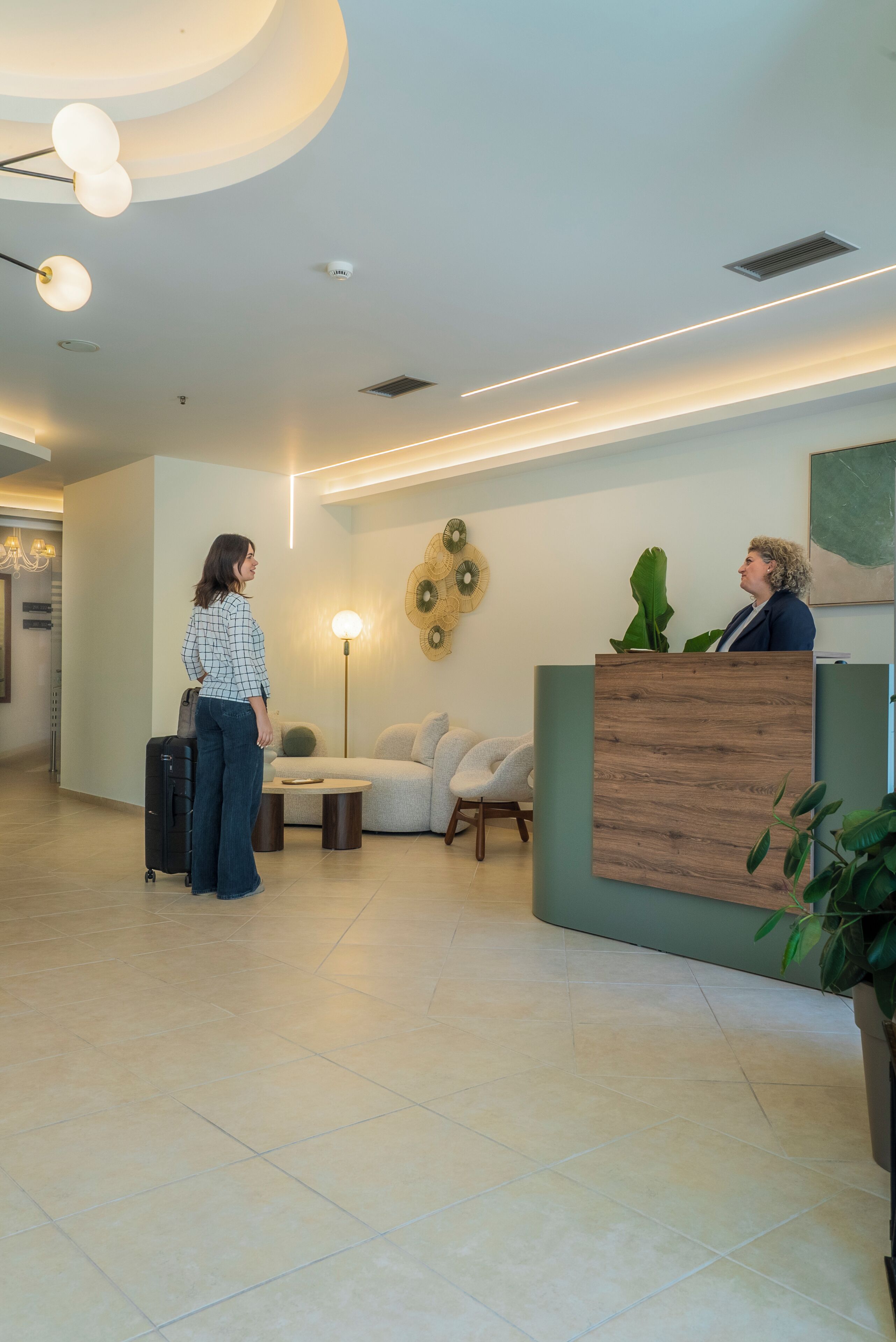 A reception area with a wooden reception desk, a seating area with a lamp, and a wall-mounted fan.