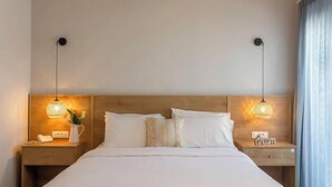 A large bed with a wooden frame, two bedside tables with lamps, and a nightstand with a phone and a lamp. - Telesilla Hotel (Corfu)