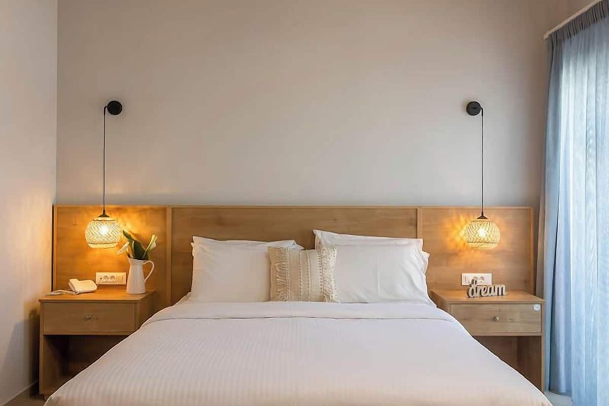 A large bed with a wooden frame, two bedside tables with lamps, and a nightstand with a phone and a lamp.