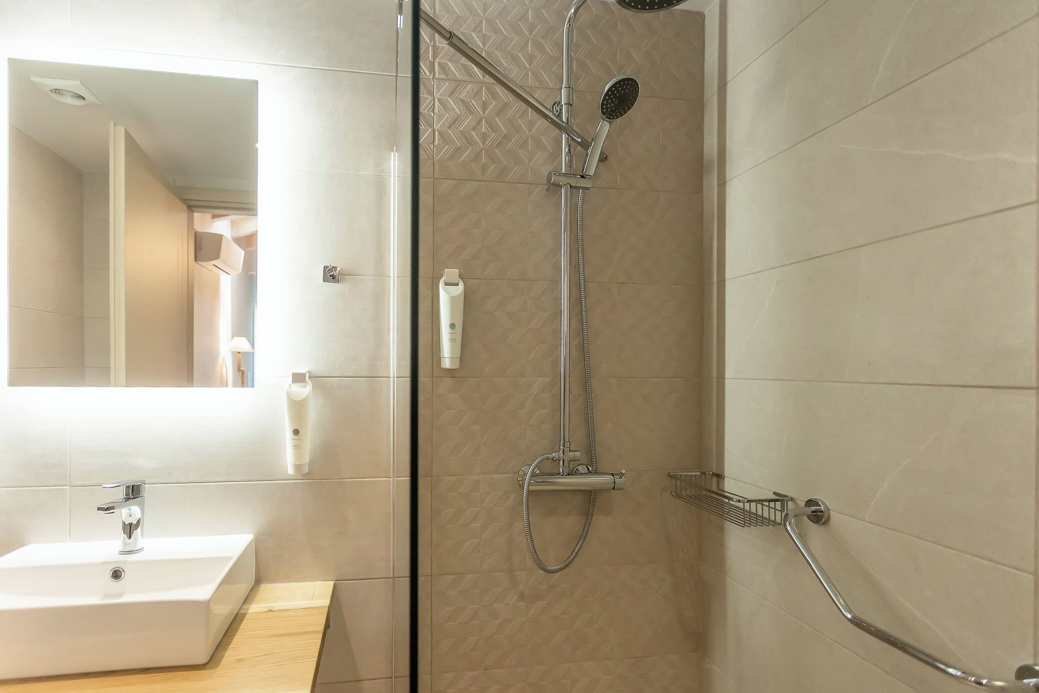 A bathroom with a glass-enclosed shower, a sink, and a mirror.
