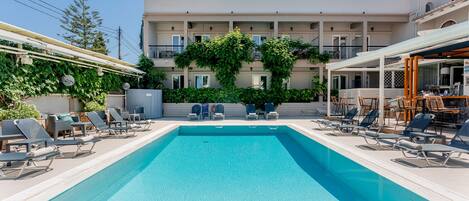 En säsongsöppen utomhuspool, parasoller och solstolar