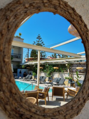 Un espace aménagé au bord de la piscine, avec des chaises longues et une vue à travers un miroir circulaire.
