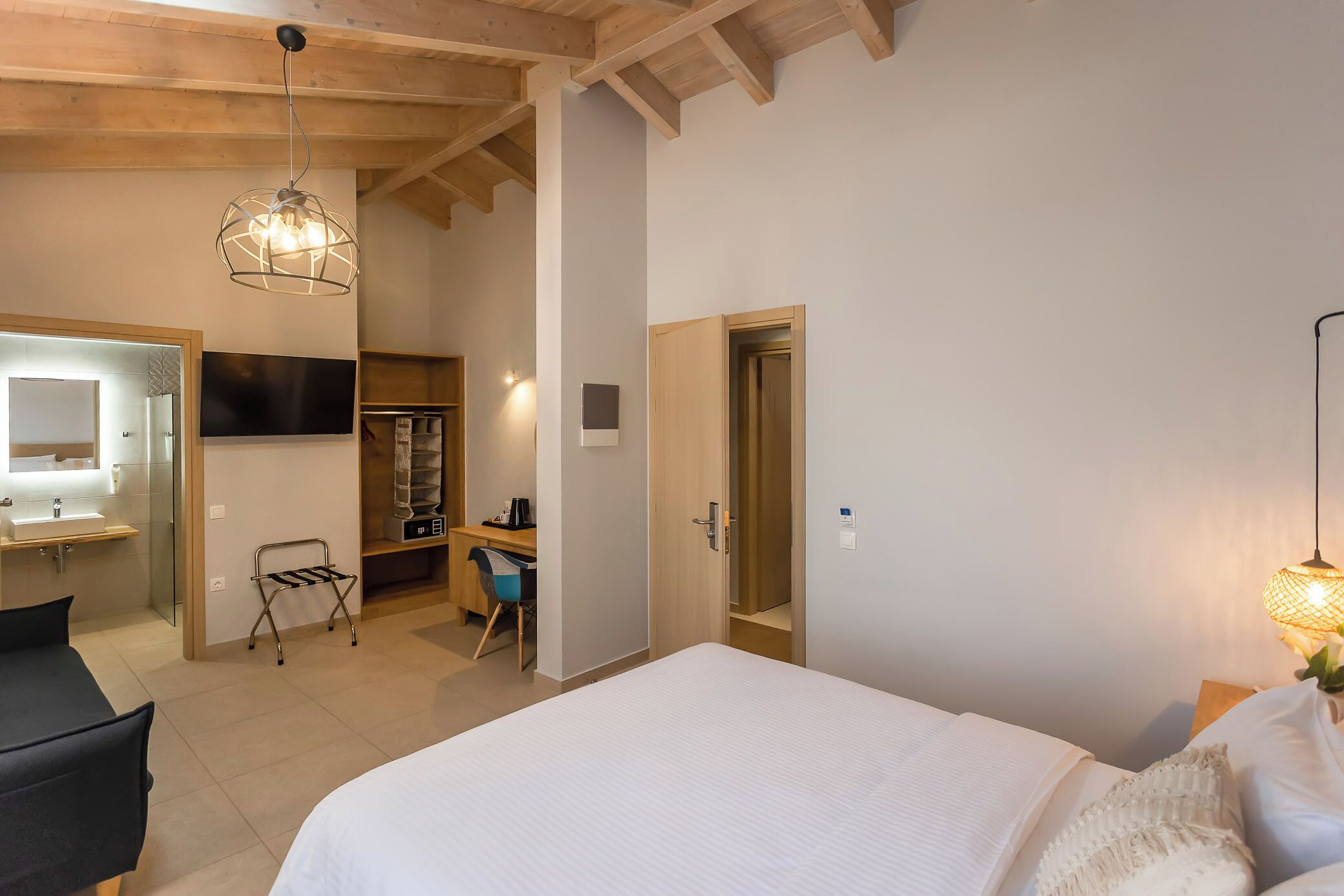 Habitación de hotel con cama, escritorio, silla, televisor y baño.