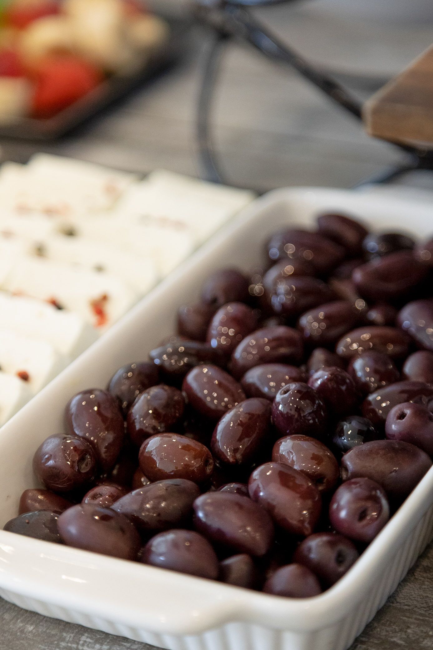 A white ceramic dish filled with dark purple olives.