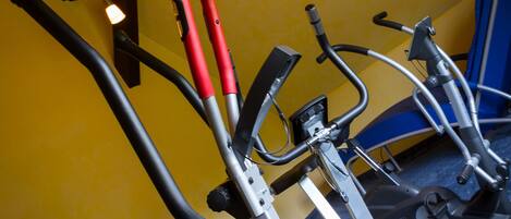Varias bicicletas estáticas en una habitación con paredes amarillas y un tapete azul en el suelo.