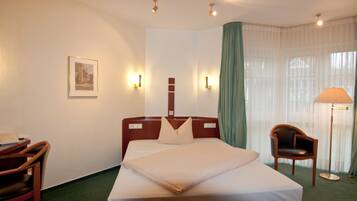 Ein Hotelzimmer mit einem Bett, einem Sessel, einem Schreibtisch und einer Lampe.