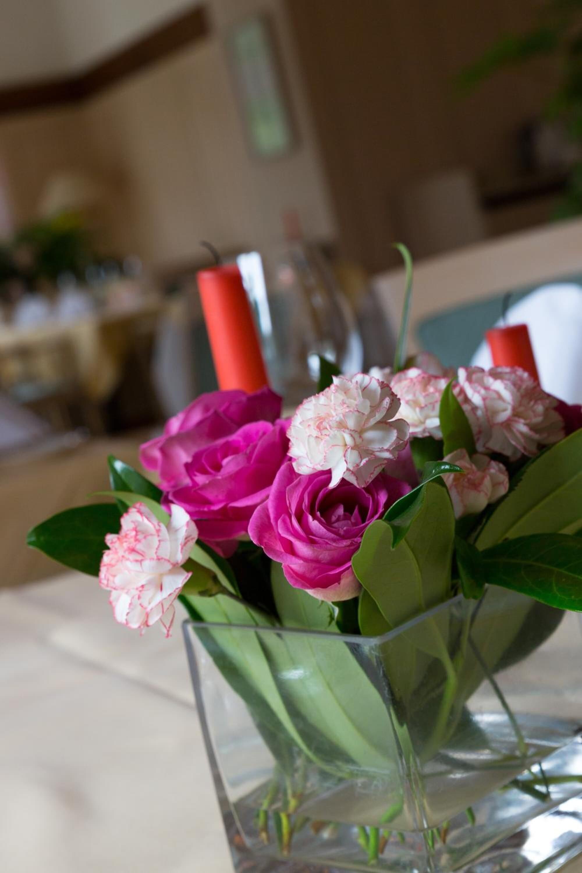 Un jarrón de cristal transparente con flores rosadas y blancas sobre una mesa.