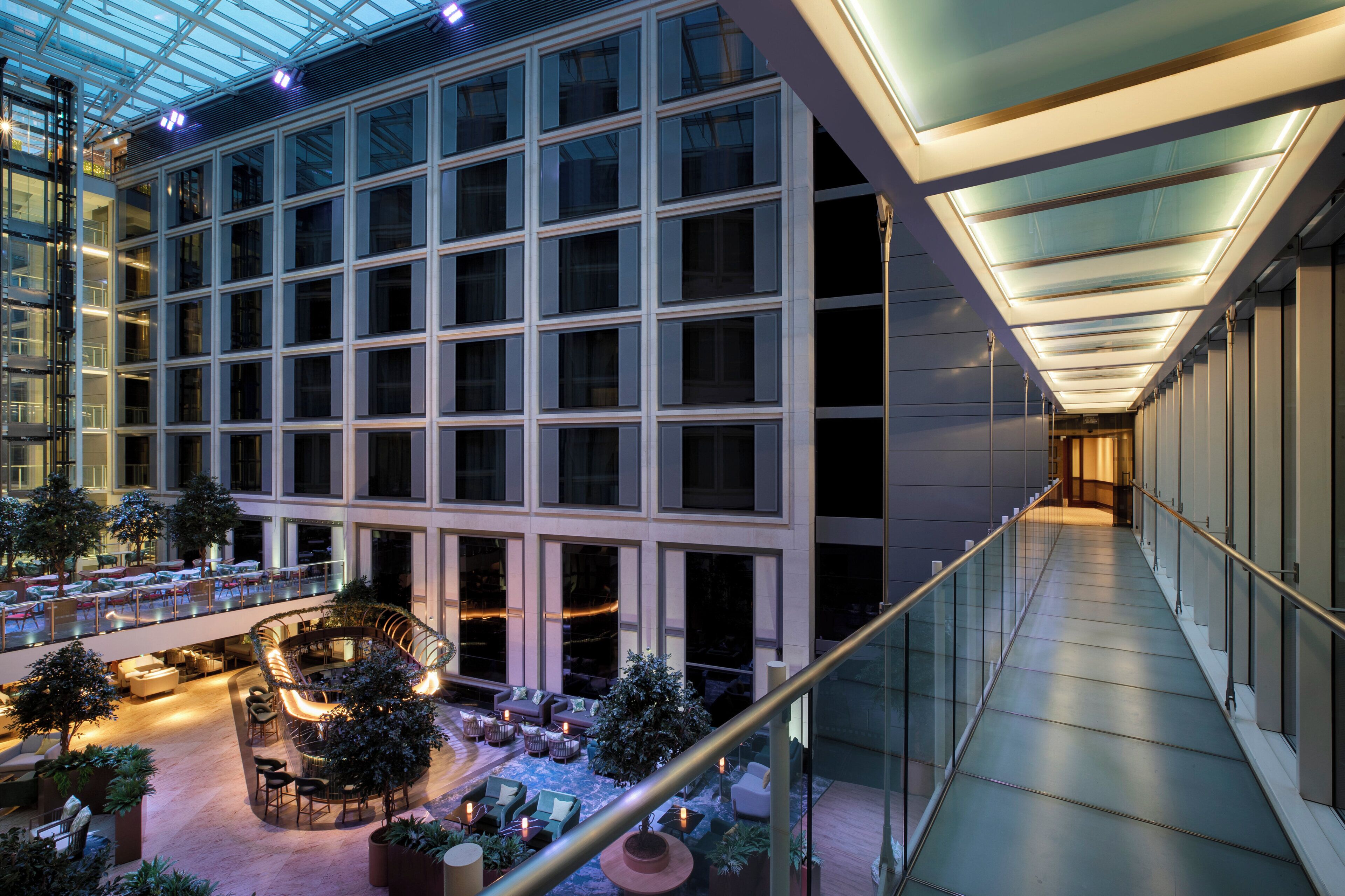 A modern hotel interior with a spacious lobby, multiple seating areas, and a glass atrium.