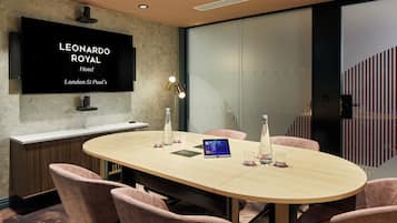A conference room with a long table, chairs, a flat-screen TV, and a bottle of water.