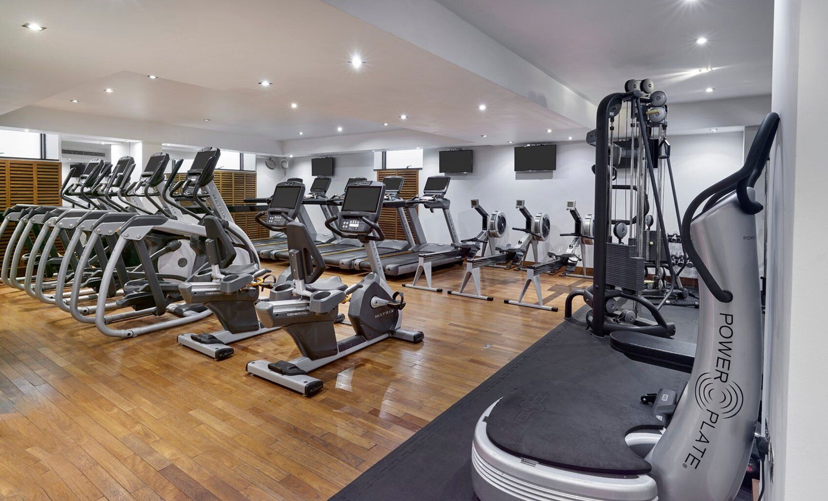 Un gimnasio con cintas de correr, elípticas y equipo de pesas.