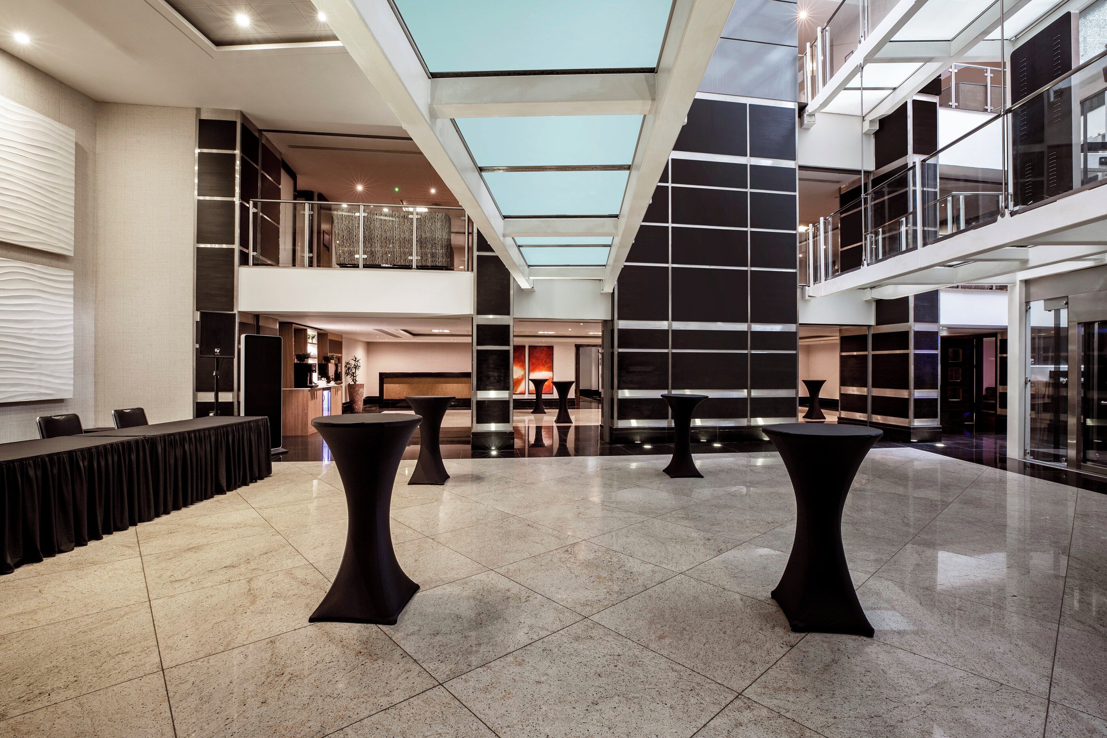 A spacious lobby with a high ceiling, a long reception desk, and multiple seating areas.
