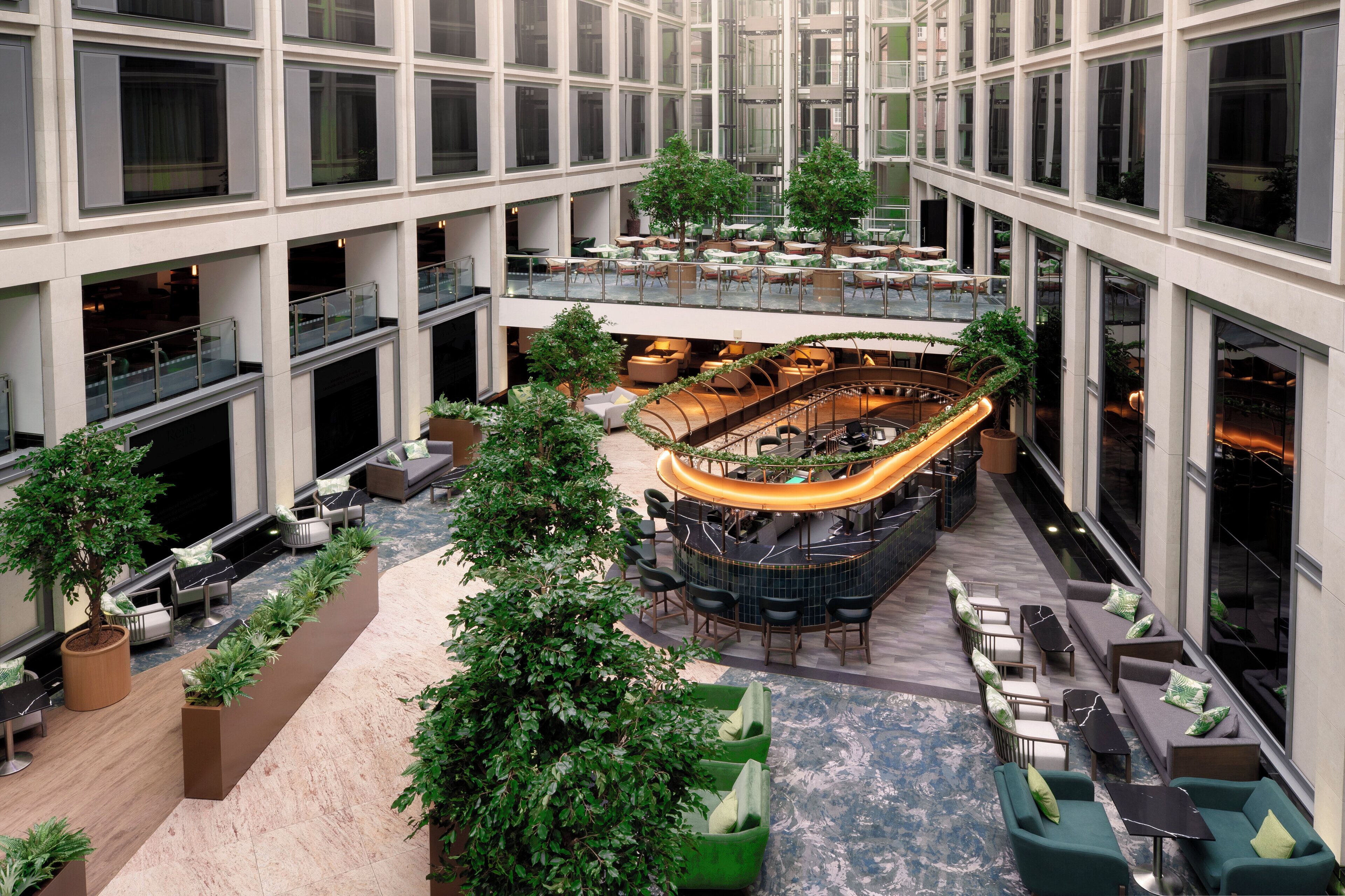 A multi-level atrium with a central bar area, seating arrangements, and greenery.