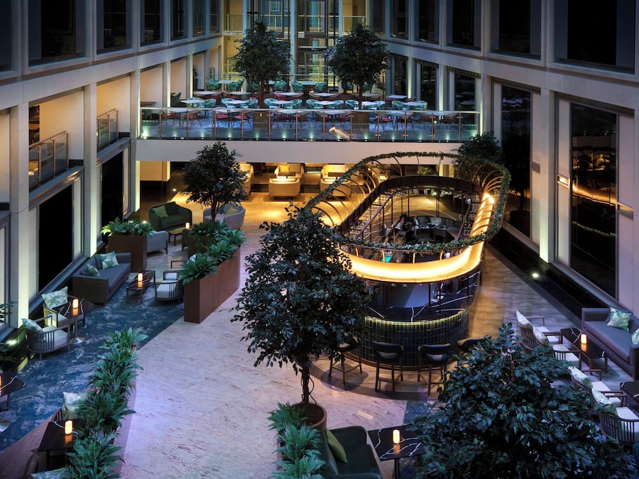 A multi-level indoor atrium with seating areas, a central bar, and a staircase.