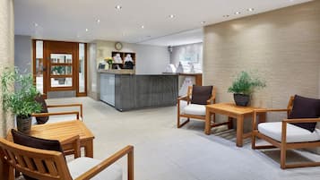 A reception area with wooden furniture, a reception desk, and a clock on the wall.