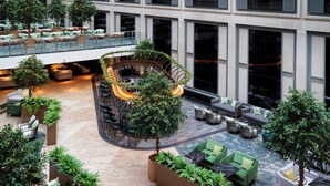 Un vaste atrium intérieur doté de nombreux espaces de détente, d’un escalier central et d’une végétation luxuriante.