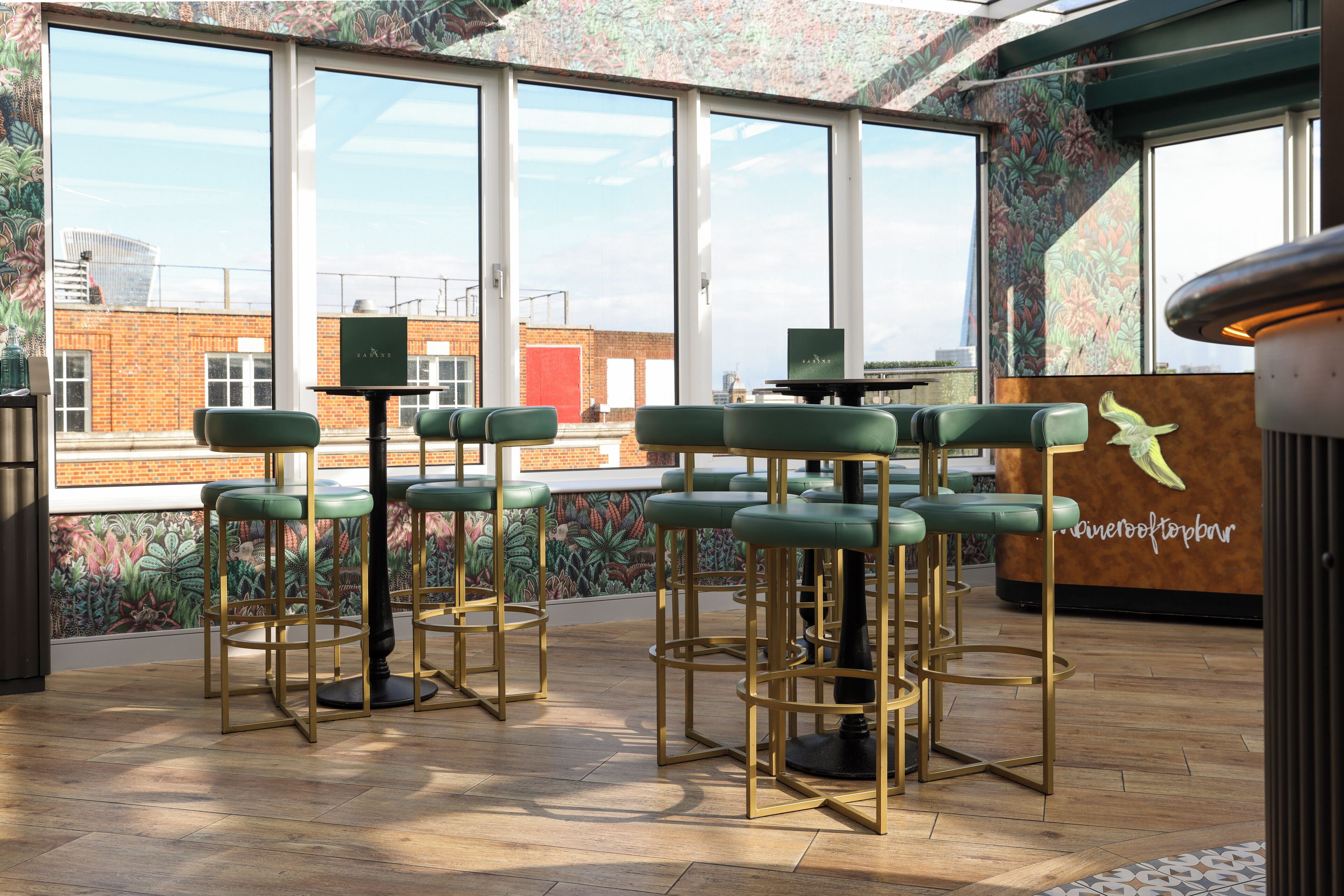 A bar area with green bar stools and a mural of tropical plants on the wall.